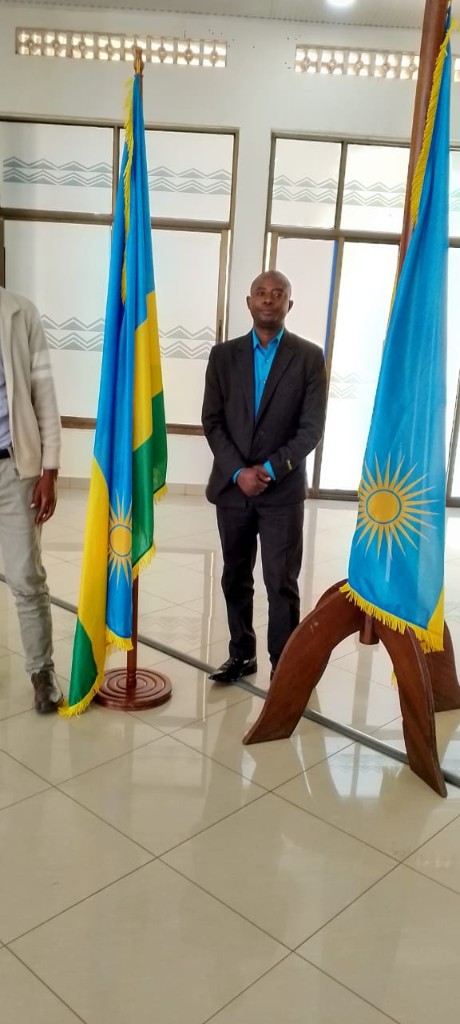 Me Habanabakize Daniel standing between Rwandan flags after taking the oath